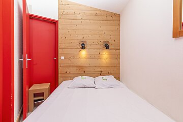 A small bedroom with a bed and a red door