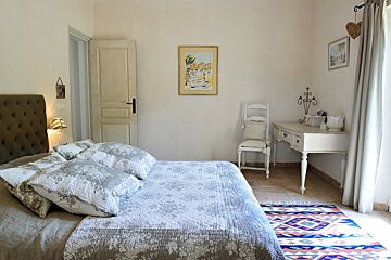 A bedroom with a painting on the wall above the bed
