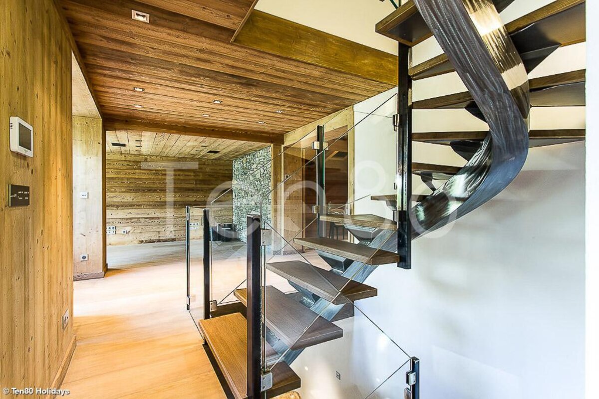 A spiral staircase with a glass railing and wooden steps