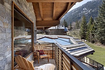 A balcony with a chair and a table with a view of the mountains