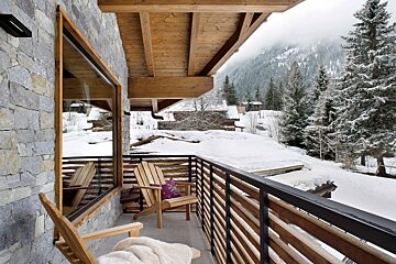 A balcony with chairs and a view of snowy mountains