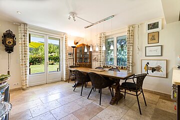 A dining room with a table and chairs and a clock on the wall