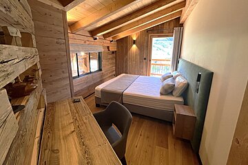 A bedroom with a large bed and a desk