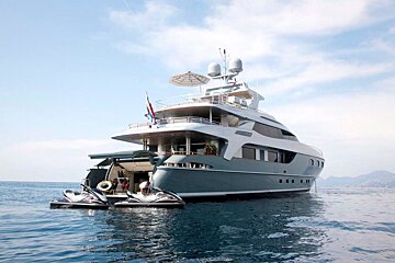 A large yacht with jet skis attached to it