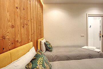 A bedroom with two beds and a wooden wall