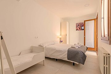 A bedroom with a bed a crib and a picture on the wall