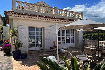 A white umbrella sits in front of a house with white shutters