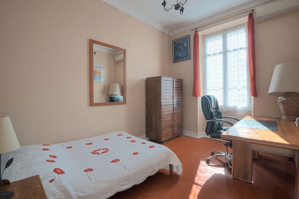 A bedroom with a bed a desk and a mirror