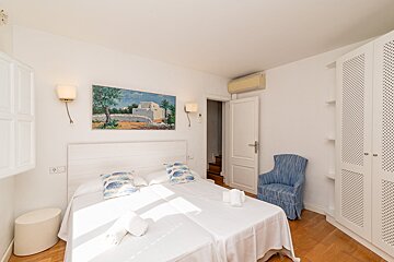A bedroom with two beds a chair and a painting on the wall