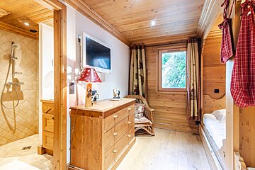 A bedroom with a dresser and a television on the wall