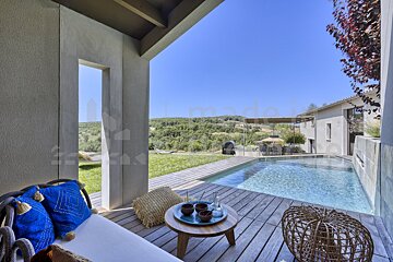A wooden deck with a swimming pool in the background