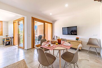 A dining room with a table and chairs and a flat screen tv