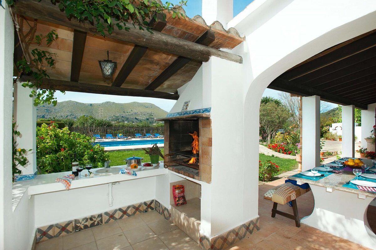 A patio area with a bbq and a pool in the background