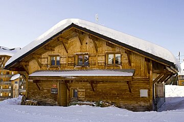 A wooden chalet is covered in snow