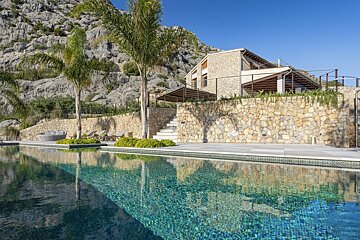 A large swimming pool in front of a stone house
