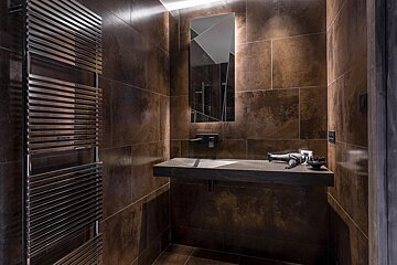 A bathroom with brown tiles and a towel rack
