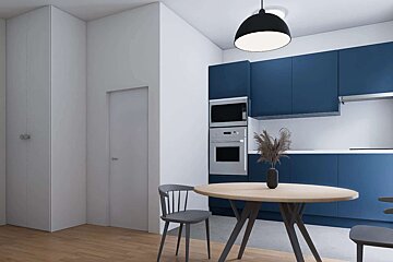 A modern kitchen and dining area with blue cabinets, white walls, wooden flooring, and a round wooden table. Built-in appliances and a black pendant light.