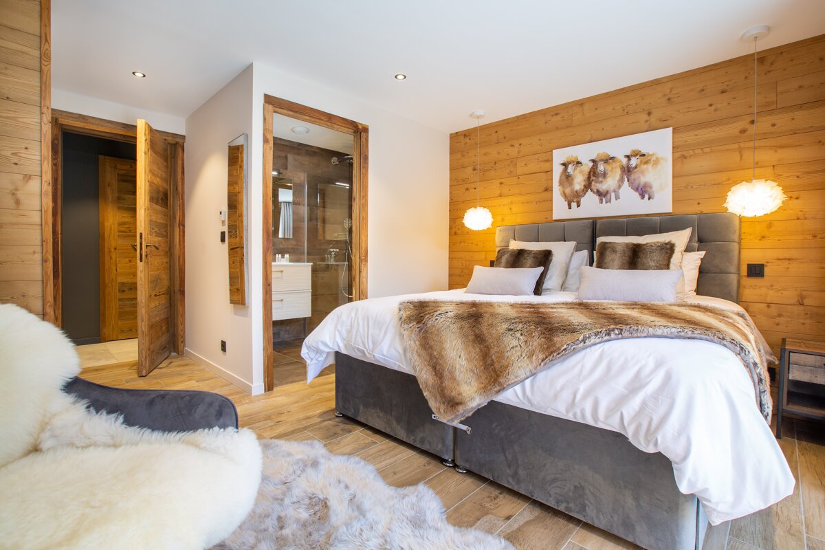A bedroom with a painting of three sheep on the wall above the bed