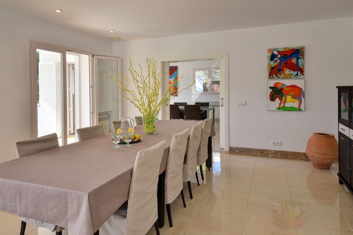 A dining room with a table and chairs and paintings on the wall