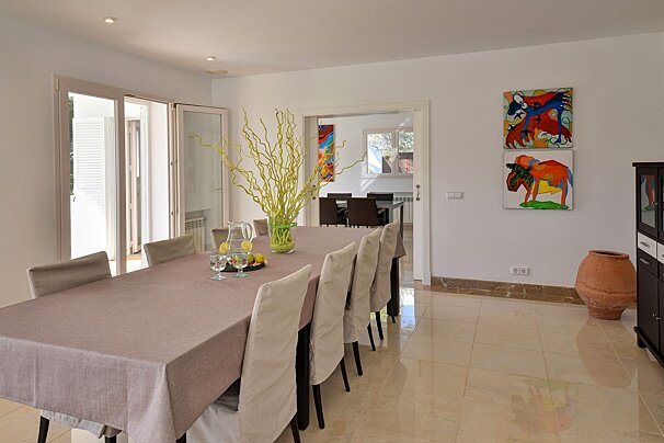 A dining room with a table and chairs and paintings on the wall