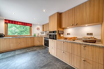 A kitchen with wooden cabinets and a clock on the wall