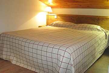 A bed with a checkered blanket and a wooden headboard