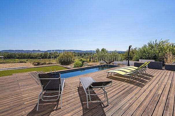 A wooden deck with chairs and a swimming pool with made in provence written on the bottom