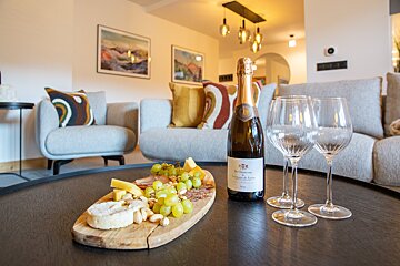 A bottle of champagne sits on a table next to two wine glasses