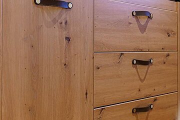 A close up of a wooden dresser with leather handles