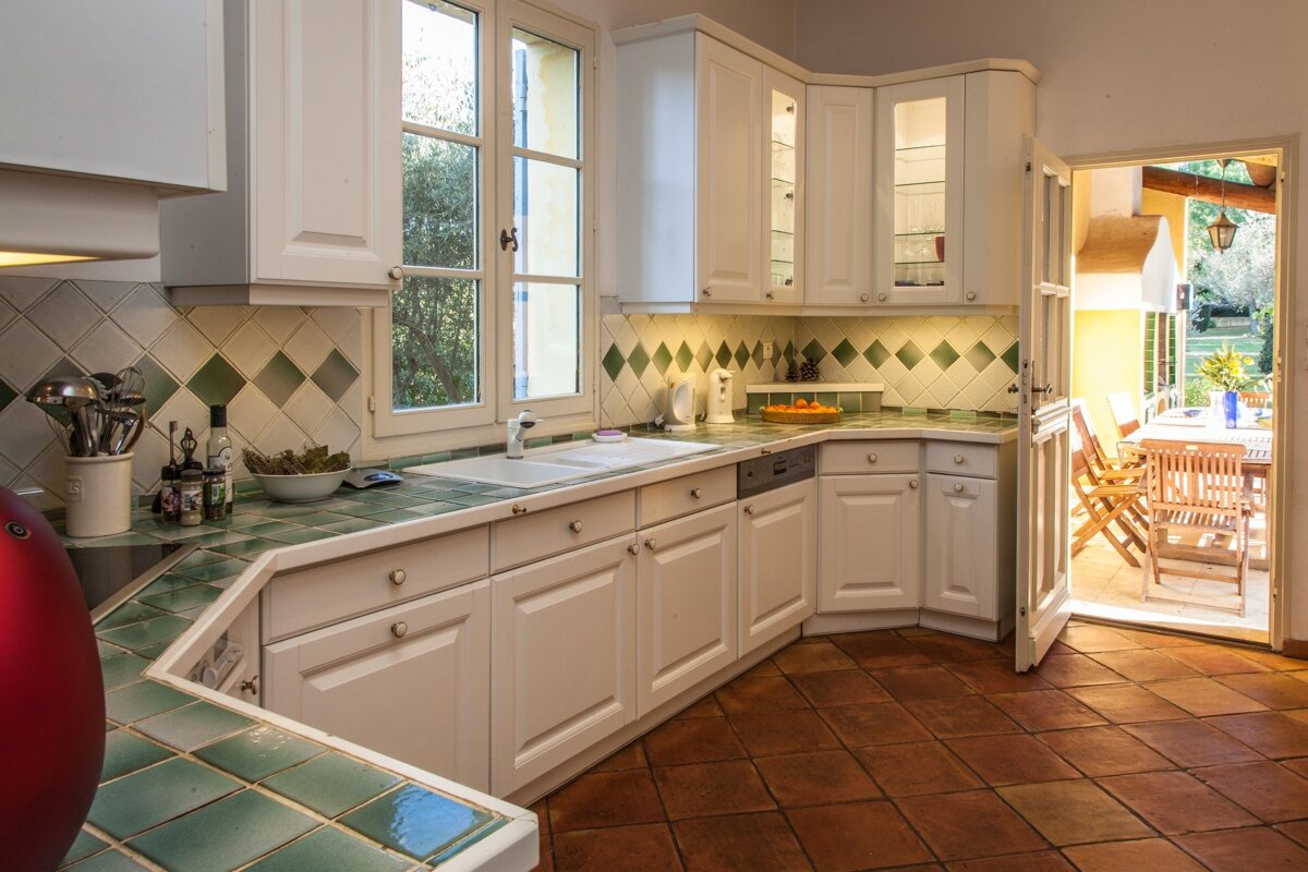 A kitchen with white cabinets and green tiles