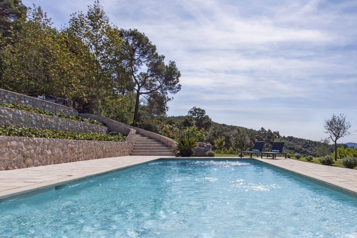 A large swimming pool surrounded by chairs and trees
