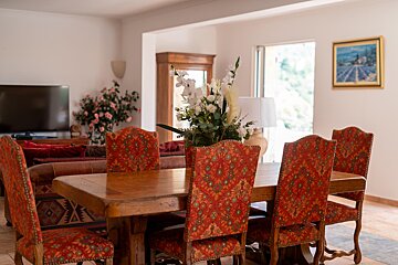 A dining room table with red chairs and a vase of flowers on it