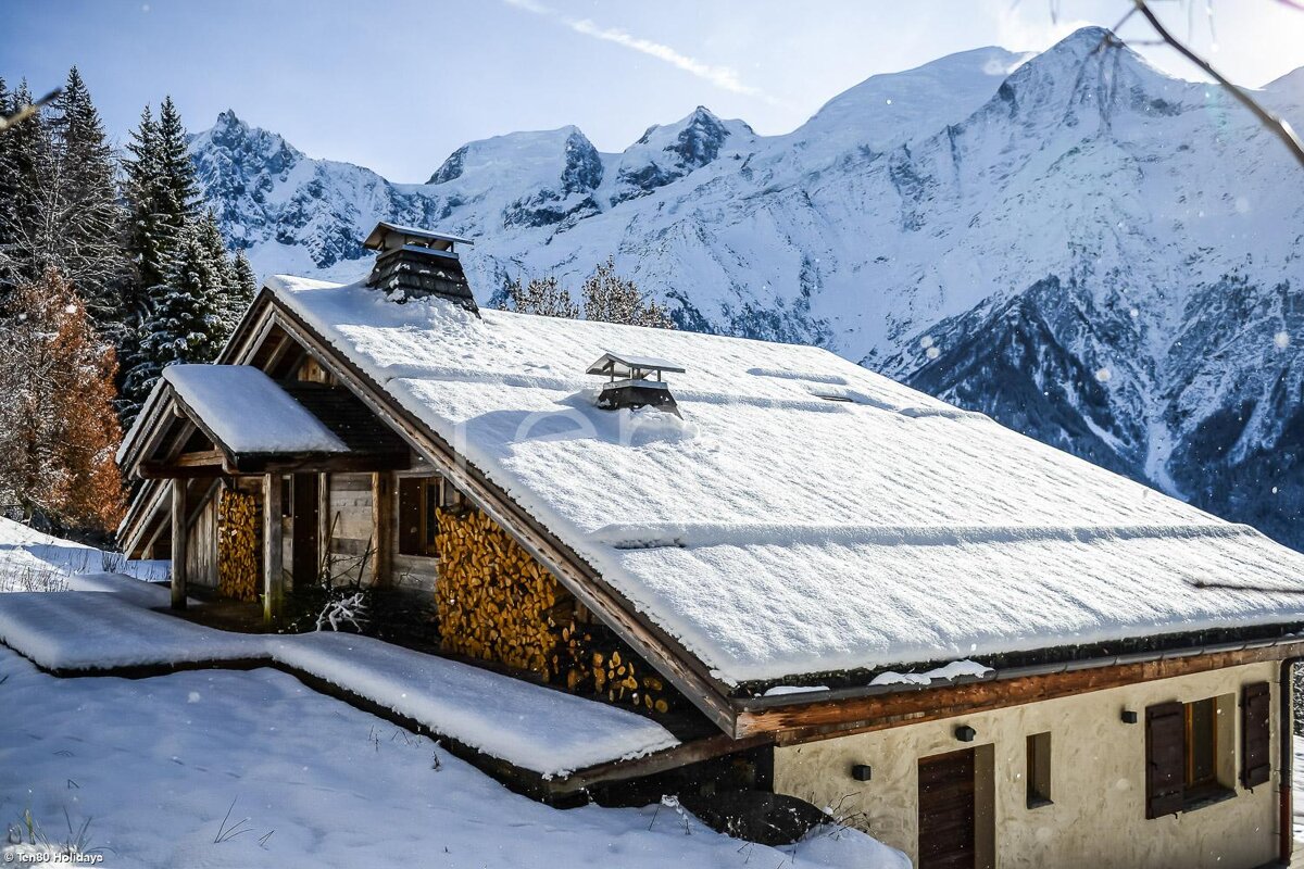 A snow covered house with mountains in the background