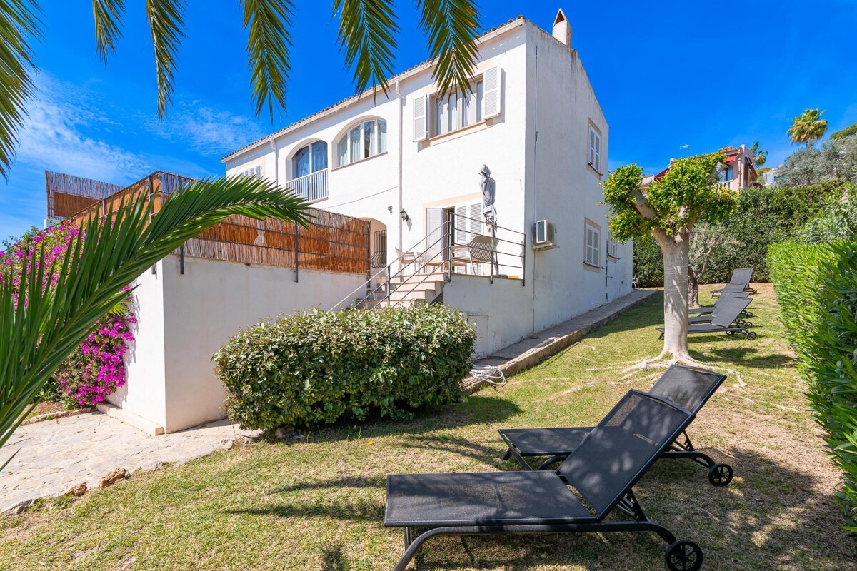 Two black lounge chairs sit in front of a white house