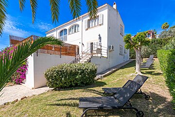 Two black lounge chairs sit in front of a white house