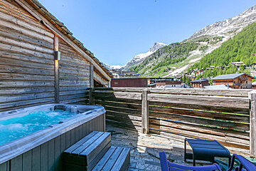 A hot tub on a balcony with a mountain in the background