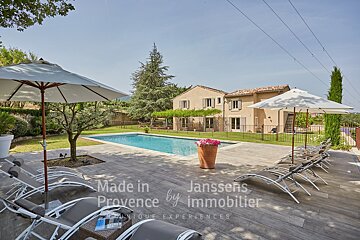 A large swimming pool surrounded by chairs and umbrellas with the words made in provence by immobilier on the bottom