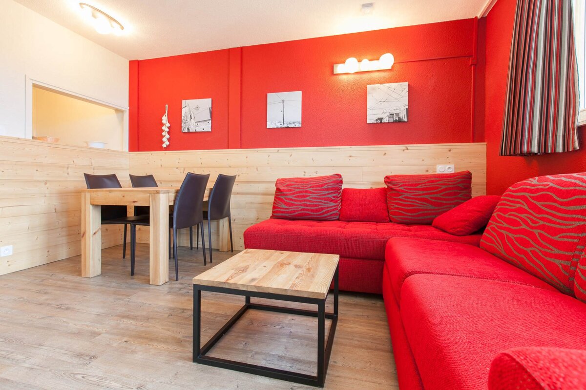 A living room with a red couch and a wooden table