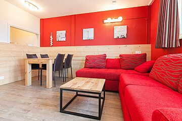 A living room with a red couch and a wooden table