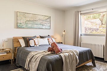 A bedroom with a large painting on the wall above the bed