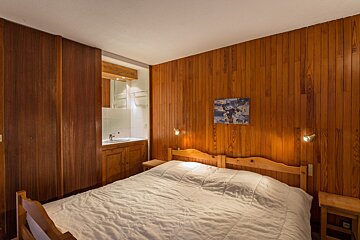 A bedroom with a bed and a picture of skiers on the wall