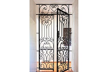 A wrought iron gate is open in a hallway