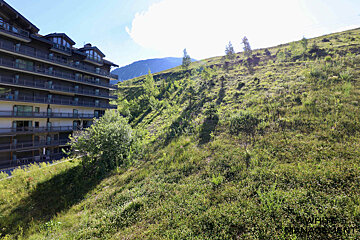 A large building sits on top of a grassy hill