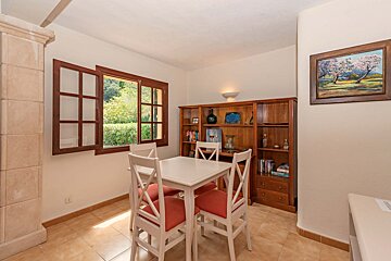 A dining room with a table and chairs and a painting on the wall