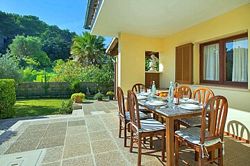 A patio with a table and chairs and a bottle of wine