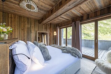 A bedroom with a large bed and lots of windows