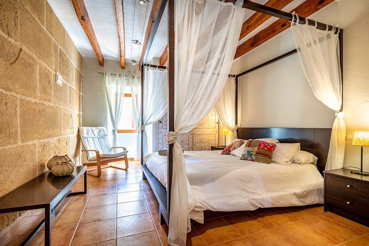 A bedroom with a canopy bed and a chair