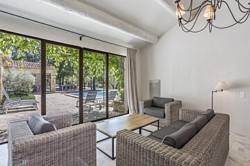 A living room with wicker furniture and a view of a pool