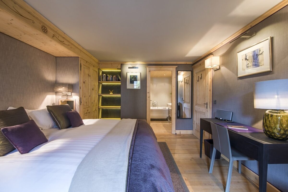 A bedroom with a large bed and a desk