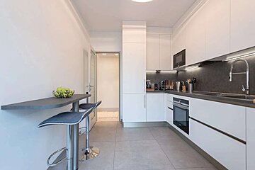 A kitchen with white cabinets and a bowl of apples on the counter
